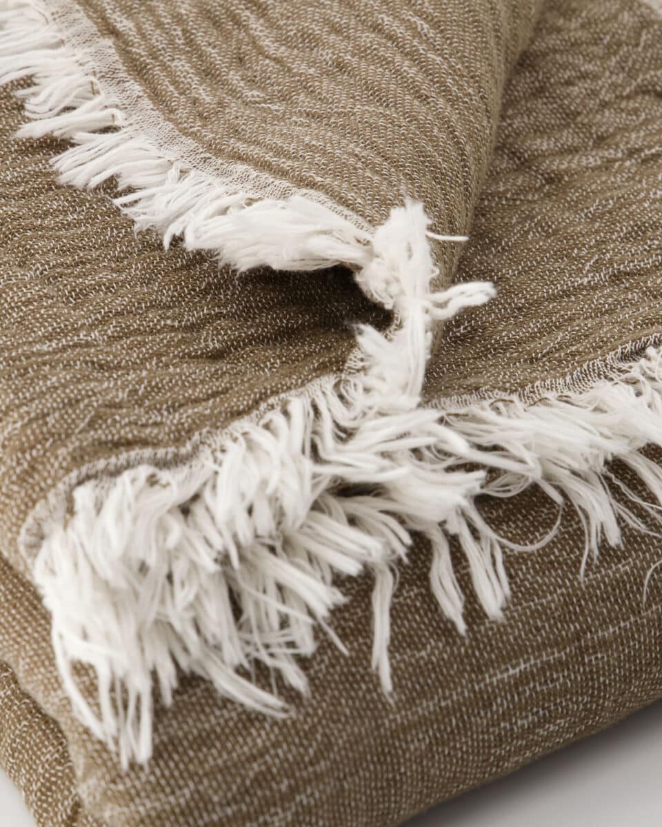 Nærbilde av pledd i lin og bomull med struktur og frynser