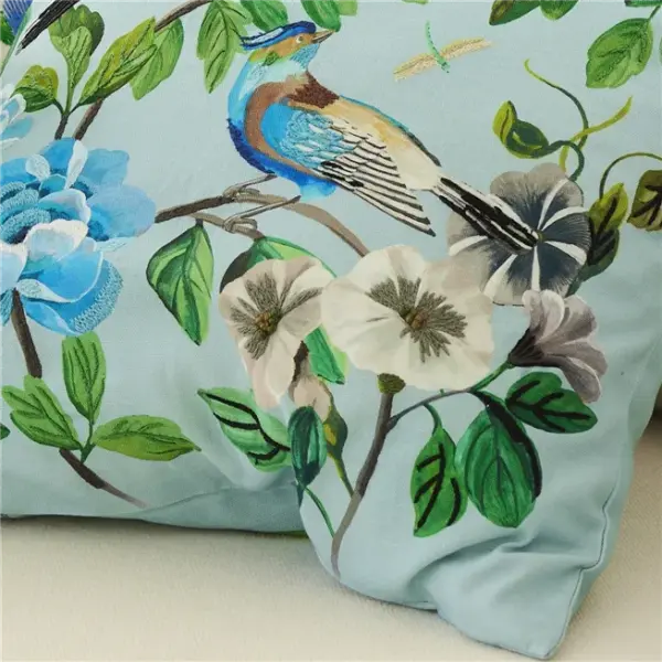 Stor pyntepute fra Designers Guild med blomster og fugler brodert på bomullscanvas i dyp cobaltblå tone.