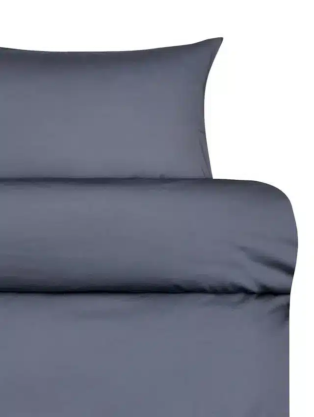 Satengsengesett i denimblå med luksuriøs mykhet og avslappet, matt finish. Skjulte knapper og moderne design for et stilrent soverom.