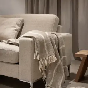 Mykt og lunt ullpledd i varm beige tone. 100 % ren ull – gjør sofakosen komplett med naturlig komfort og elegant uttrykk.