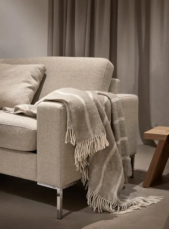 Mykt og lunt ullpledd i varm beige tone. 100 % ren ull – gjør sofakosen komplett med naturlig komfort og elegant uttrykk.