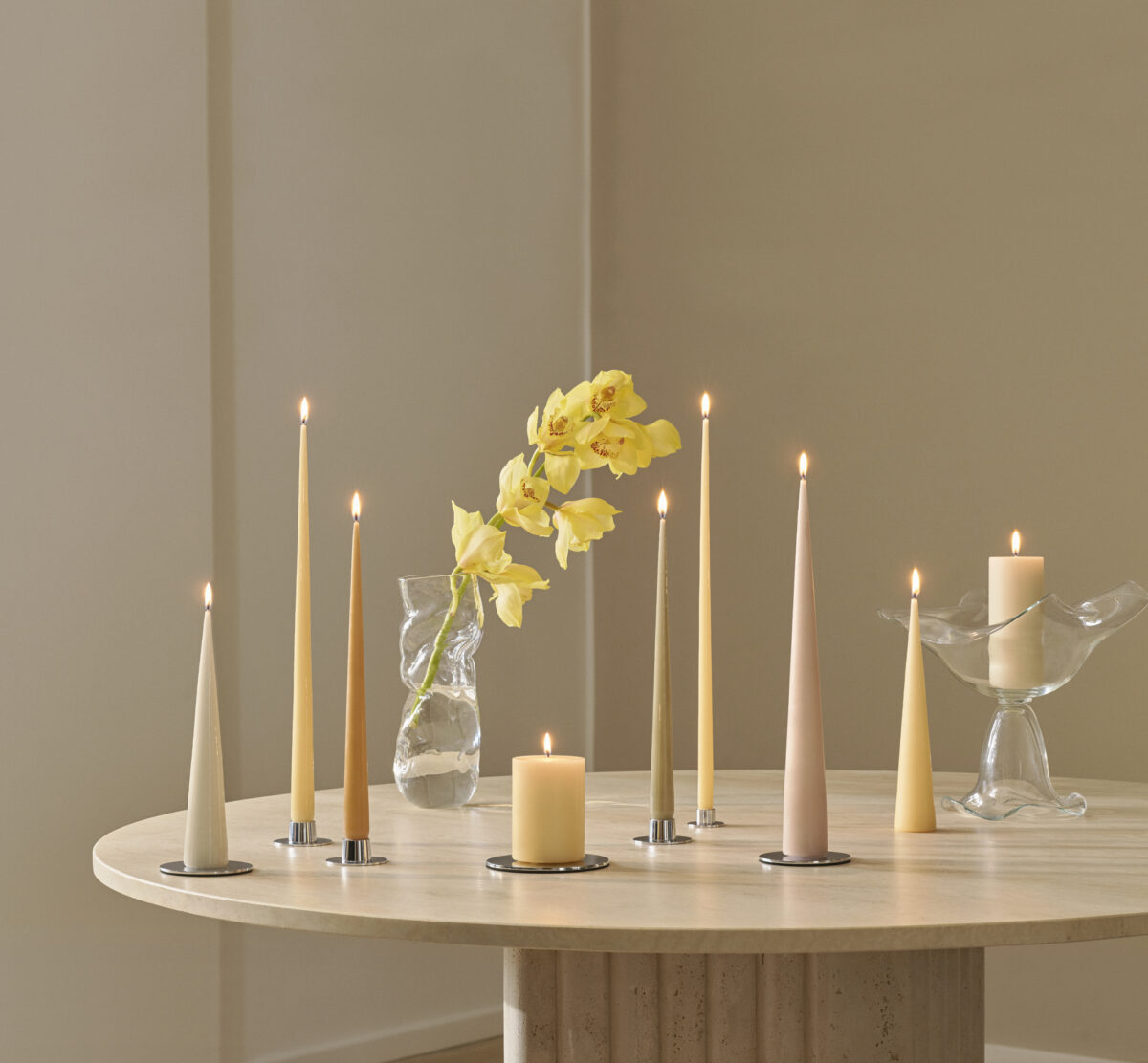 Bord med stearinlys i pastellfarger og blomster i vase – vårens interiørtrender 2026
