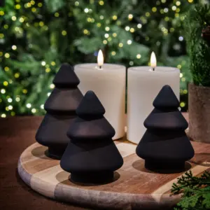 Mørkebrune glasstrær i frostet kakao fra Hadeland Glassverk, dekorert på bord med tente stearinlys.