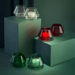Lyslykter i klart glass med bobler fra Hadeland Glassverk, arrangert i moderne miljø sammen med røde og grønne varianter.