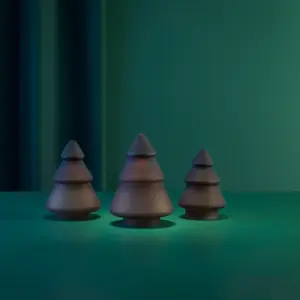 Frostede bruntonede glasstrær fra Hadeland Glassverk som juledekorasjon ved tente lys.