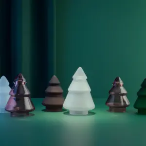 Tre ulike glasstrær i frostet glass fra Hadeland Glassverk, stående på grønn bakgrunn.