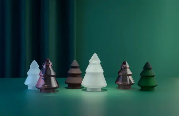 Tre ulike glasstrær i frostet glass fra Hadeland Glassverk, stående på grønn bakgrunn.