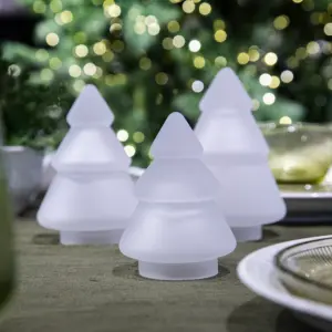 Hvite frostede glasstrær fra Hadeland Glassverk arrangert på grønn overflate i vinterlig belysning.