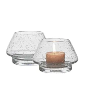 Gran lyslykt i klart glass med bobler fra Hadeland Glassverk, med tent telys som reflekterer flammen vakkert.