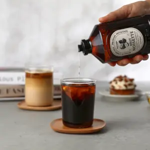 Bacanha Brut Noisette helles i et glass iskaffe på et rundt underlag i rolige, lyse omgivelser.