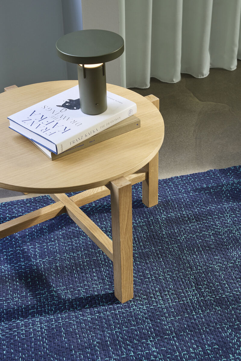 BringMe oppladbar og dimbar bordlampe Mini i Metallic Dark Green fra Hübsch plassert på et rundt trebord, med varmt tent lys.